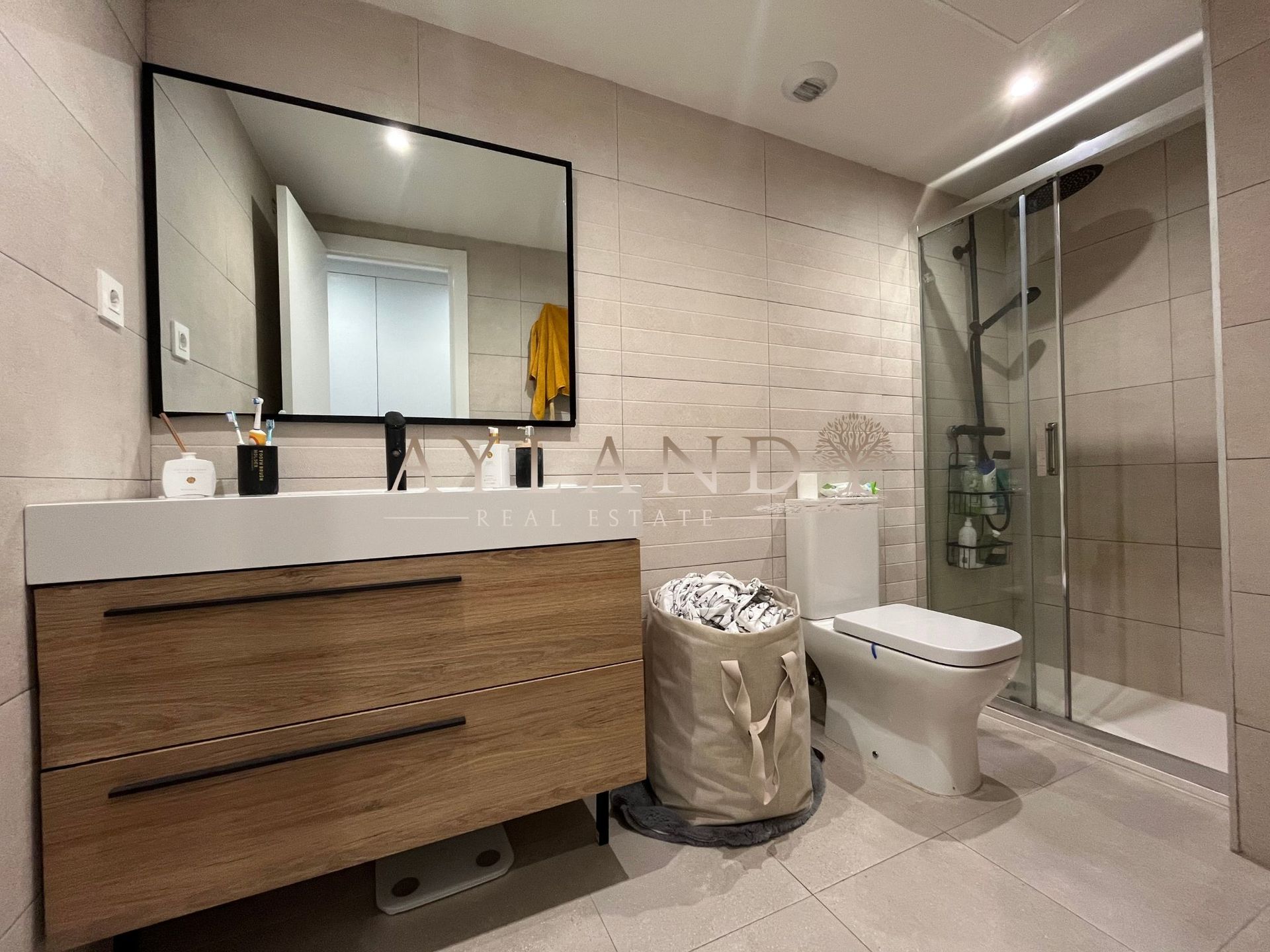Baño con mueble de madera, espejo y ducha acristalada
