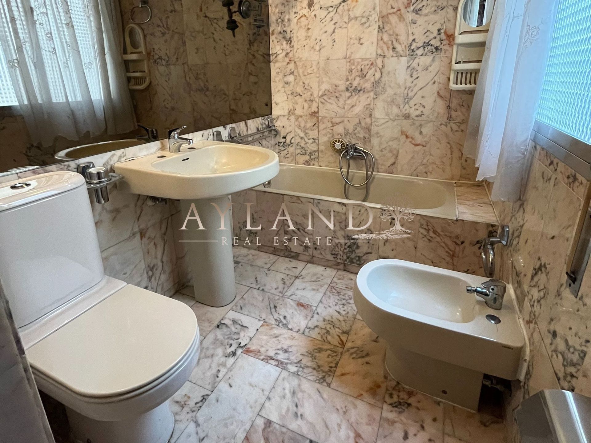 Baño alicatado en mármol, con lavabo, inodoro y bidé