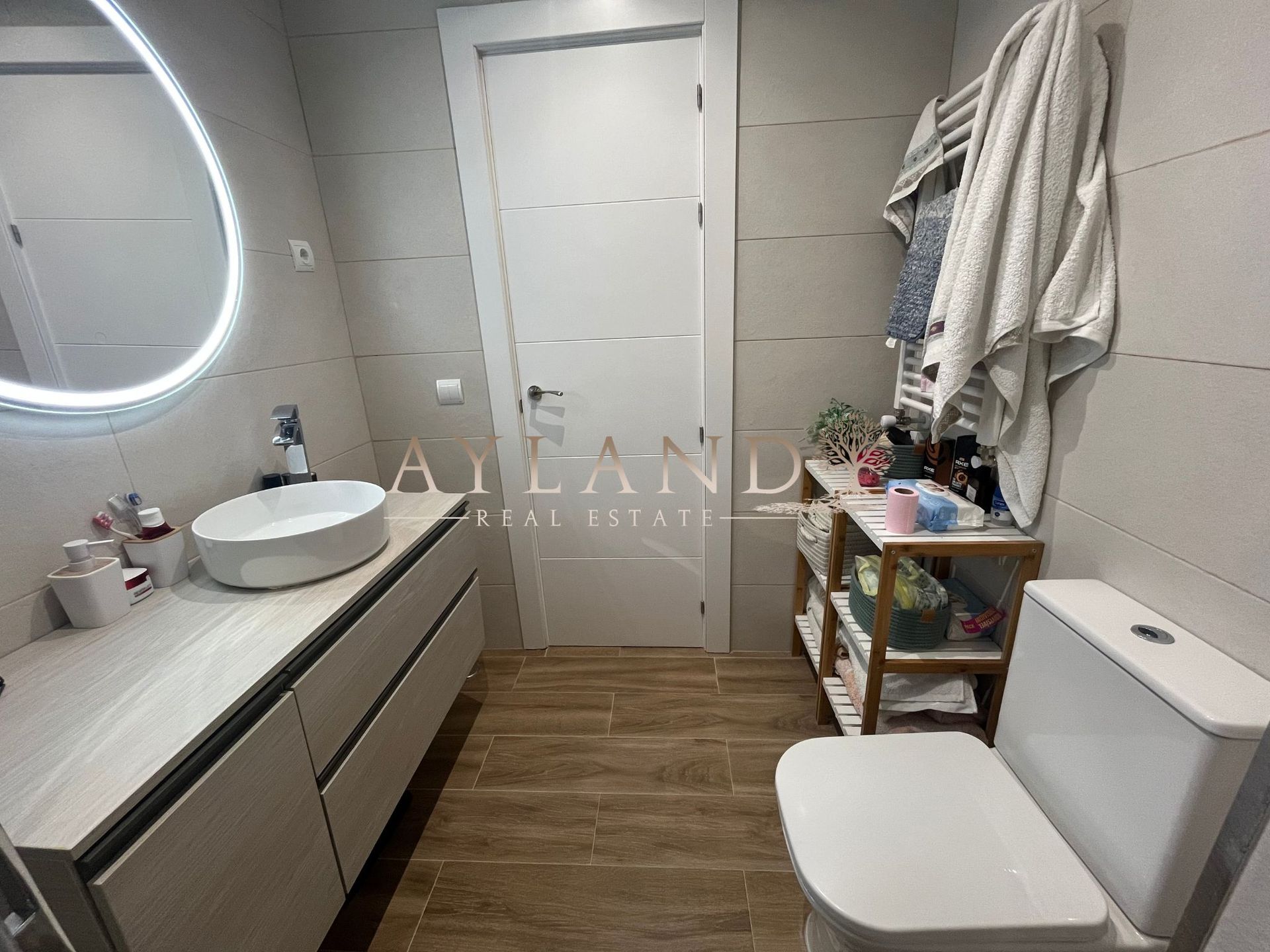 El baño, con lavabo sobre encimera y espejo circular retroiluminado