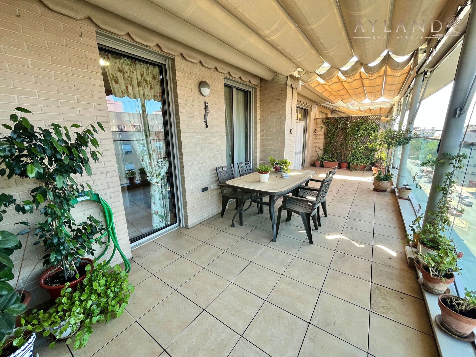 La mesa de la terraza, bajo el toldo