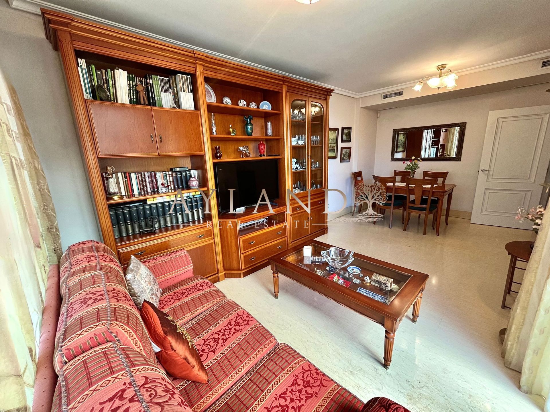 El salón, con la librería de madera y el comedor al fondo